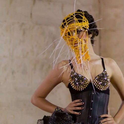 Imagen de chica con vestido moderno negro y decoración de cuerdas y palillos en la cara